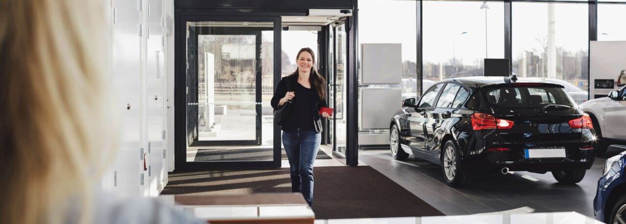 Kvinna passerar genom automatiska skjutdörrar på bilfirma.