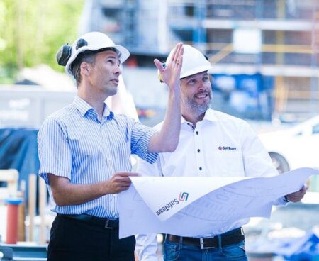 Projektledare går igenom ritning på byggarbetsplats.