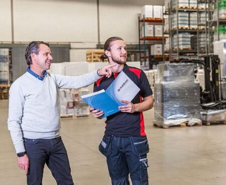 Låstekniker pratar om säkerhet med industrianställd i en lagerlokal.