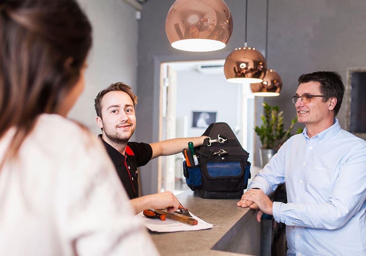 Låstekniker på serviceuppdrag pratar med man och kvinna i reception.