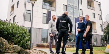 Fyra personer från fastighetsbolag och säkerhetsbolag står framför en fastighet och diskuterar upphandling av säkerhetslösningar. | SafeTeam