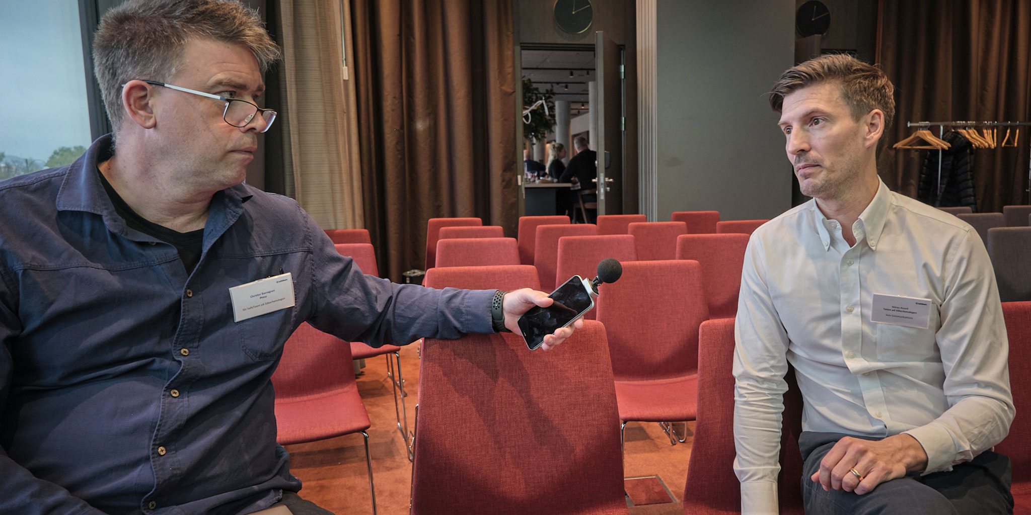 Christer Barregren till vänster intervjuar Niklas Rosell till höger i ett tomt konferensrum möblerat för biosittning.