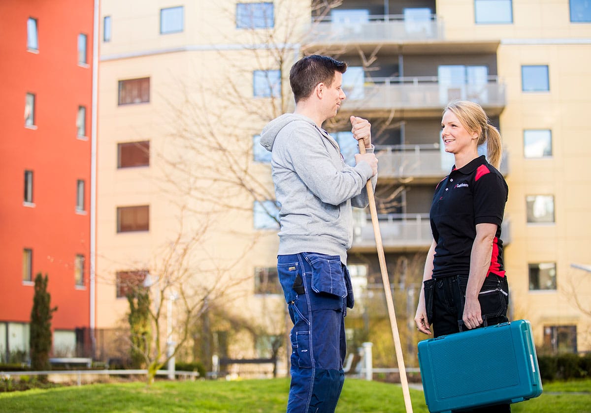 Fastighetsskötare och säkerhetstekniker från SafeTeam utanför ett flerbostadshus.