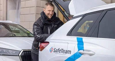 Tekniker från SafeTeam vid sin bil med öppen bagagelucka där han hämtar verktyg inför en installation av säkerhetsteknik.