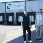 Installation av brandlarm där en brandlarmsprojektör från SafeTeam står bredvid kunden utanför lokalen till Constellation Cold Logistics i Göteborg. I bakgrunden syns leveransportar till fastigheten och fasadskylt med Constellation Cold Logistics företagslogotyp.