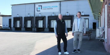 Installation av brandlarm där en brandlarmsprojektör från SafeTeam står bredvid kunden utanför lokalen till Constellation Cold Logistics i Göteborg. I bakgrunden syns leveransportar till fastigheten och fasadskylt med Constellation Cold Logistics företagslogotyp.