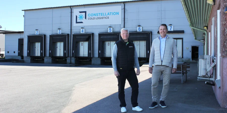 Installation av brandlarm där en brandlarmsprojektör från SafeTeam står bredvid kunden utanför lokalen till Constellation Cold Logistics i Göteborg. I bakgrunden syns leveransportar till fastigheten och fasadskylt med Constellation Cold Logistics företagslogotyp.