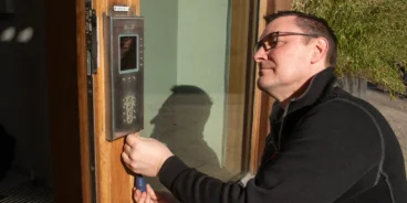 En installationstekniker monterar en porttelefon från Aptus hos en brf.